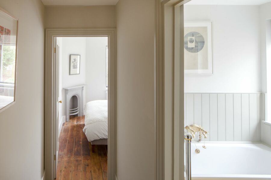 Hallway with pale, earthy paint tones looking through to a bedroom and a bathroom.